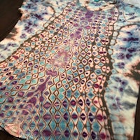 a blue and purple tie dye t - shirt on a table